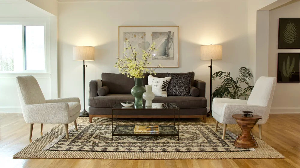 A living room with a charcoal sofa, cream armchairs and layered rugs